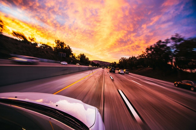 car driving into sunset